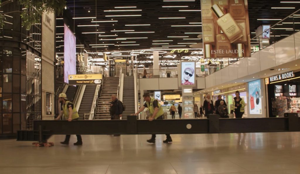 16 stalen balken op rolletjes door Schiphol